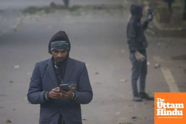 New Delhi: People walk along a foggy street as cold weather and reduced visibility