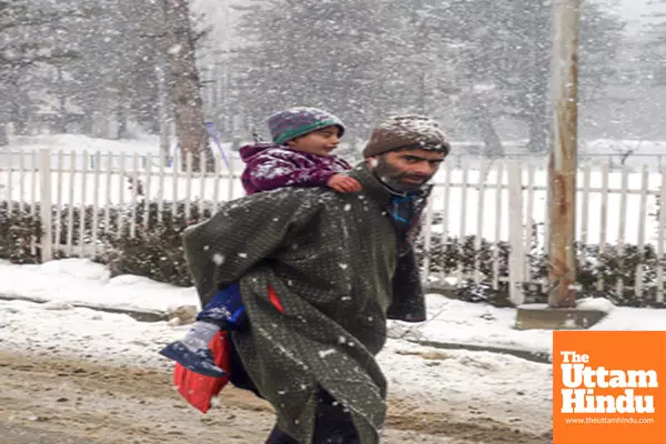 Baramulla: A man carrying a child on his back on a snow-covered road amid heavy snowfall