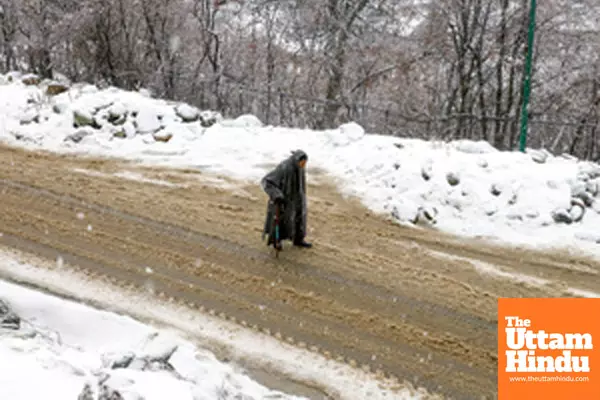 Baramulla: An elderly man walks past a snow-covered road amid heavy snowfall