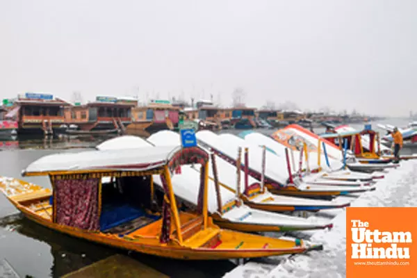 Srinagar: Snow-covered Shikara boats are moored to the bank of Dal Lake