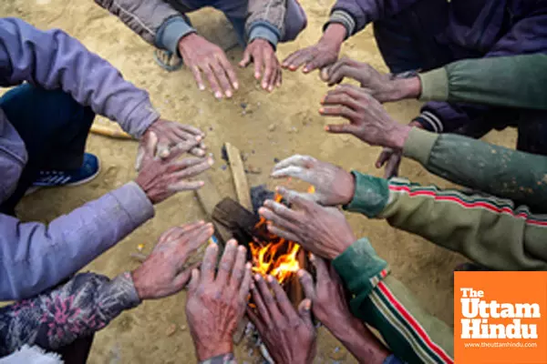 Prayagraj: Workers sit around a bonfire to keep themselves warm