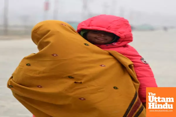 Prayagraj: A woman holds her child, both wrapped in warm clothes