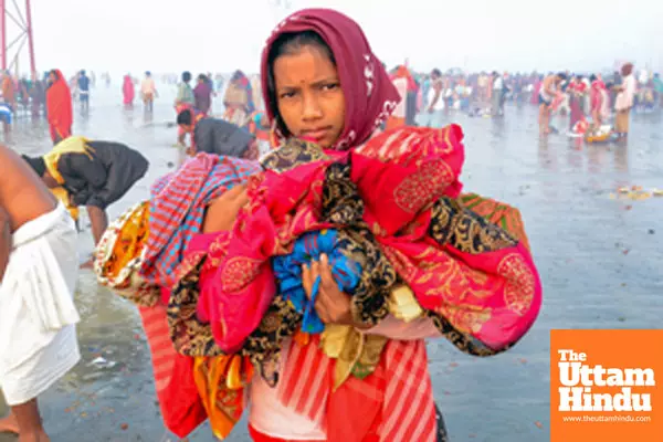 South 24 Parganas: A girl holds onto clothes of her relative during the holy dip at Gangasagar Island