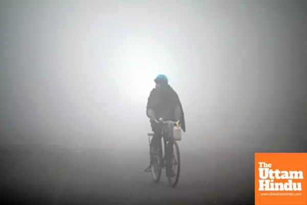 Noida: A man rides his bicycle through dense fog on a chilly winter morning