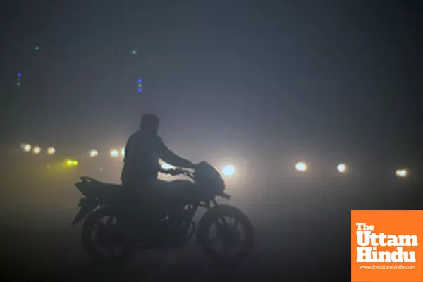 Noida: A man rides his bike through dense fog on a chilly winter morning