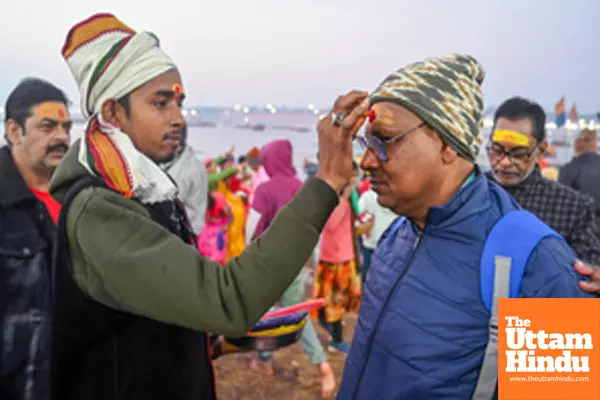 Prayagraj: A Sadhu applies Tilak to a man at Triveni Sangam