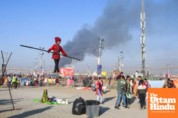 Prayagraj: A young girl performs a tightrope act at the banks of Sangam as smoke billows from a fire